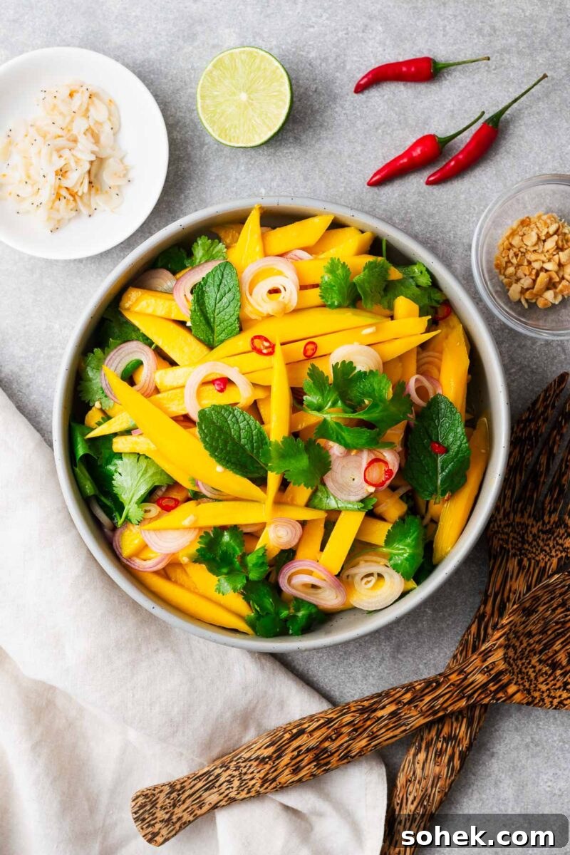 Spicy Thai Green Mango Salad (Yam Ma Muang) — Tangy Mango Thai Salad 9 A serving bowl with green mango salad next to bowls of crushed peanuts and rehydrated dried shrimp.