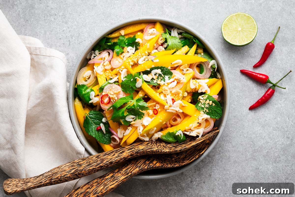 Spicy Thai Green Mango Salad (Yam Ma Muang) — Tangy Mango Thai Salad 10 A serving bowl with spicy Thai green mango salad and bamboo serving spoons.