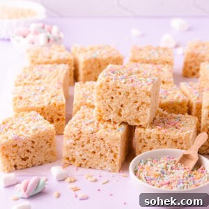Gluten-Free Rice Krispie Treats Recipe — Crispy & Chewy Bars 12 A stack of gluten free rice krispie treats on a pale purple background with a small bowl of pastel sprinkles.