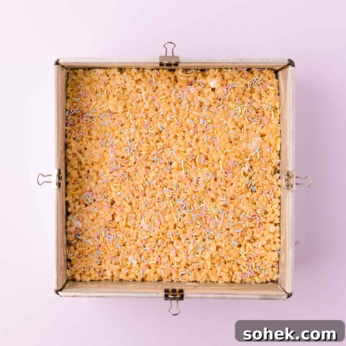 Gluten-Free Rice Krispie Treats Recipe — Crispy & Chewy Bars 10 The GF rice krispie treat mixture pressed into an even layer in the square pan, and sprinkled with pastel sprinkles.