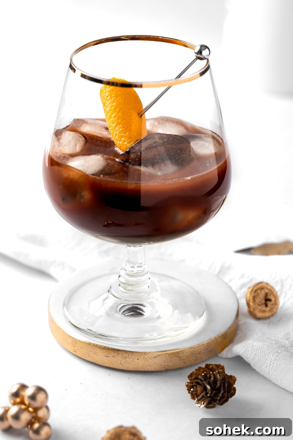 Chocolate Old Fashioned Cocktail Recipe & How to Make It 7 A chocolate old fashioned garnished with an orange peel, on a white background.