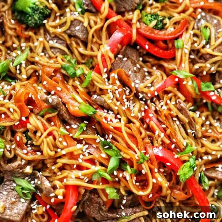 sesame garlic noodles with steak, red bell peppers, broccoli, and carrots.