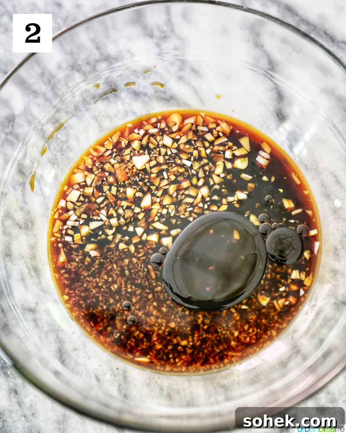 sesame garlic soy sauce in a large clear glass bowl on marble table.