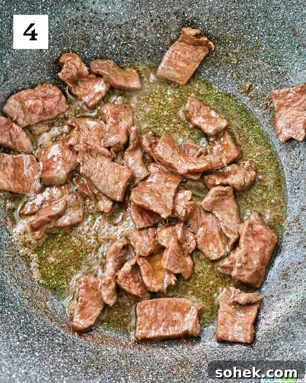 sliced steak cooking in a large wok.