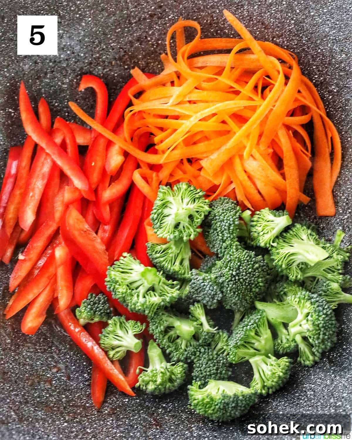 red bell peppers, carrots, and broccoli in a large wok.