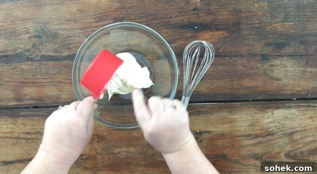 Copycat Restaurant-Style Ranch Dressing Recipe for Flavorful Salads 4 a photo of a cup measure with mayonnaise pouring into a glass bowl with a whisk to the right