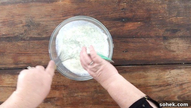 Copycat Restaurant-Style Ranch Dressing Recipe for Flavorful Salads 6 A photo of adding a ranch packet to the milk and mayonnaise mixture in a glass bowl