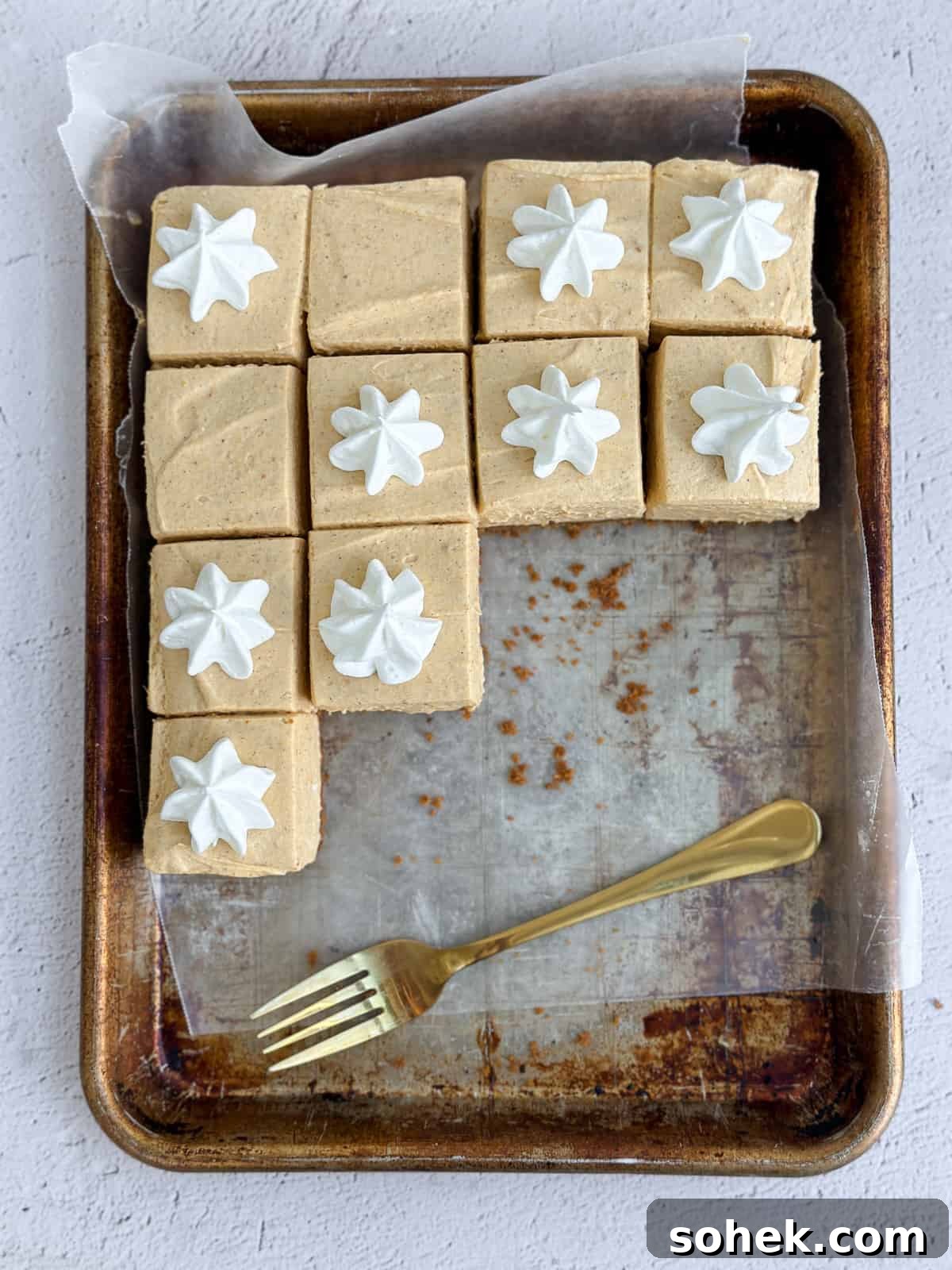No-Bake Pumpkin Cheesecake Bars — Creamy Fall Dessert Recipe 3 a bunch of the no bake pumpkin cheesecake bars on a baking sheet with a fork.