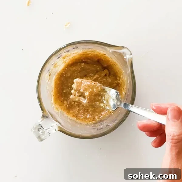 Mixed almond butter caramel on a fork in a mixing bowl.