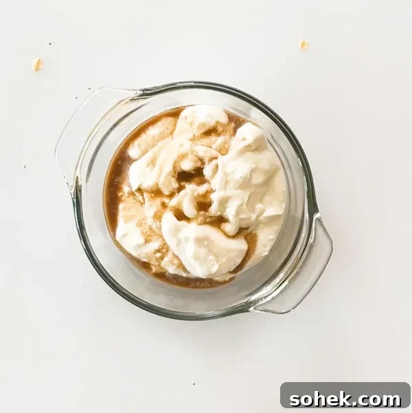 Greek yogurt and maple syrup in a glass mixing bowl.