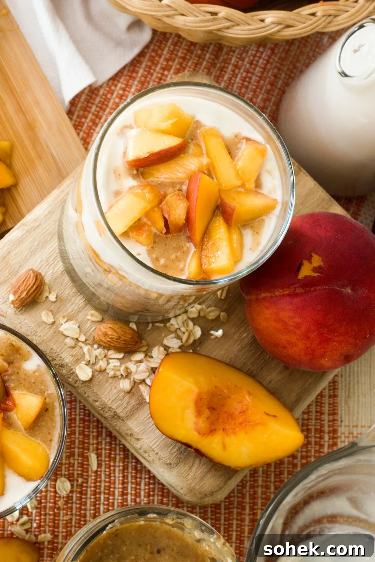 Top view of a glass full of peaches & cream overnight oats with chopped peaches.