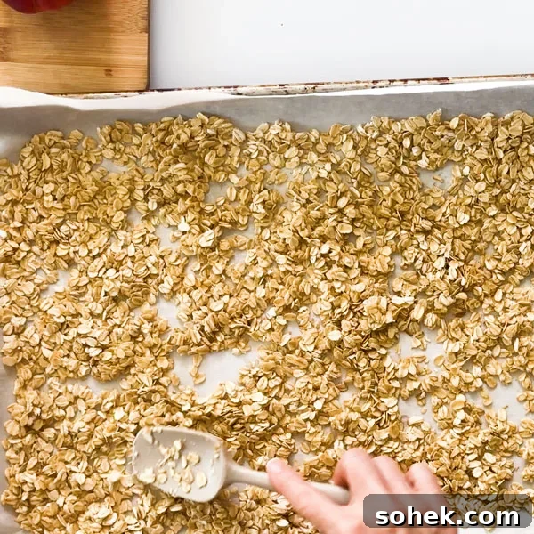 Spreading oats in a baking sheet with a spatula.