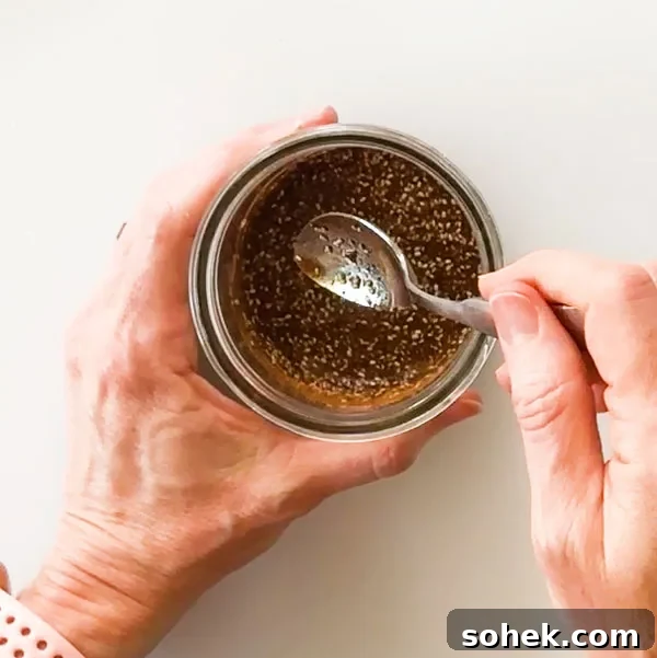 Mixing the almond butter caramel sauce in a small mason jar with a spoon.