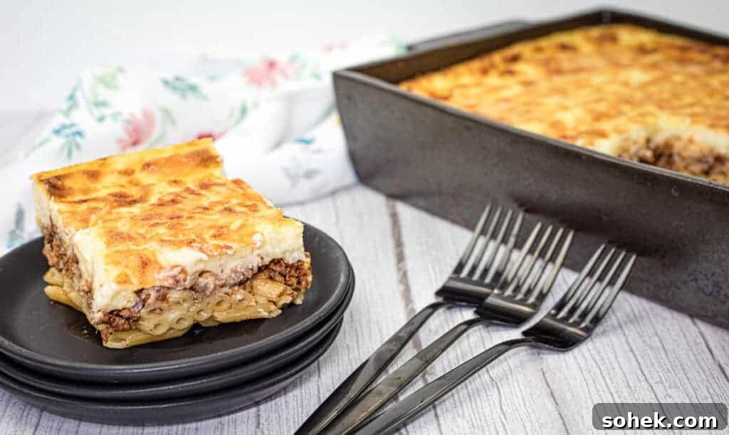 21 Quick Ground Beef Dinners That Will Have Everyone Asking Your Secret 9 A square piece of pastitsio served on a stack of black plates with three forks and a rectangular baking tray filled with the same pasta on the side.