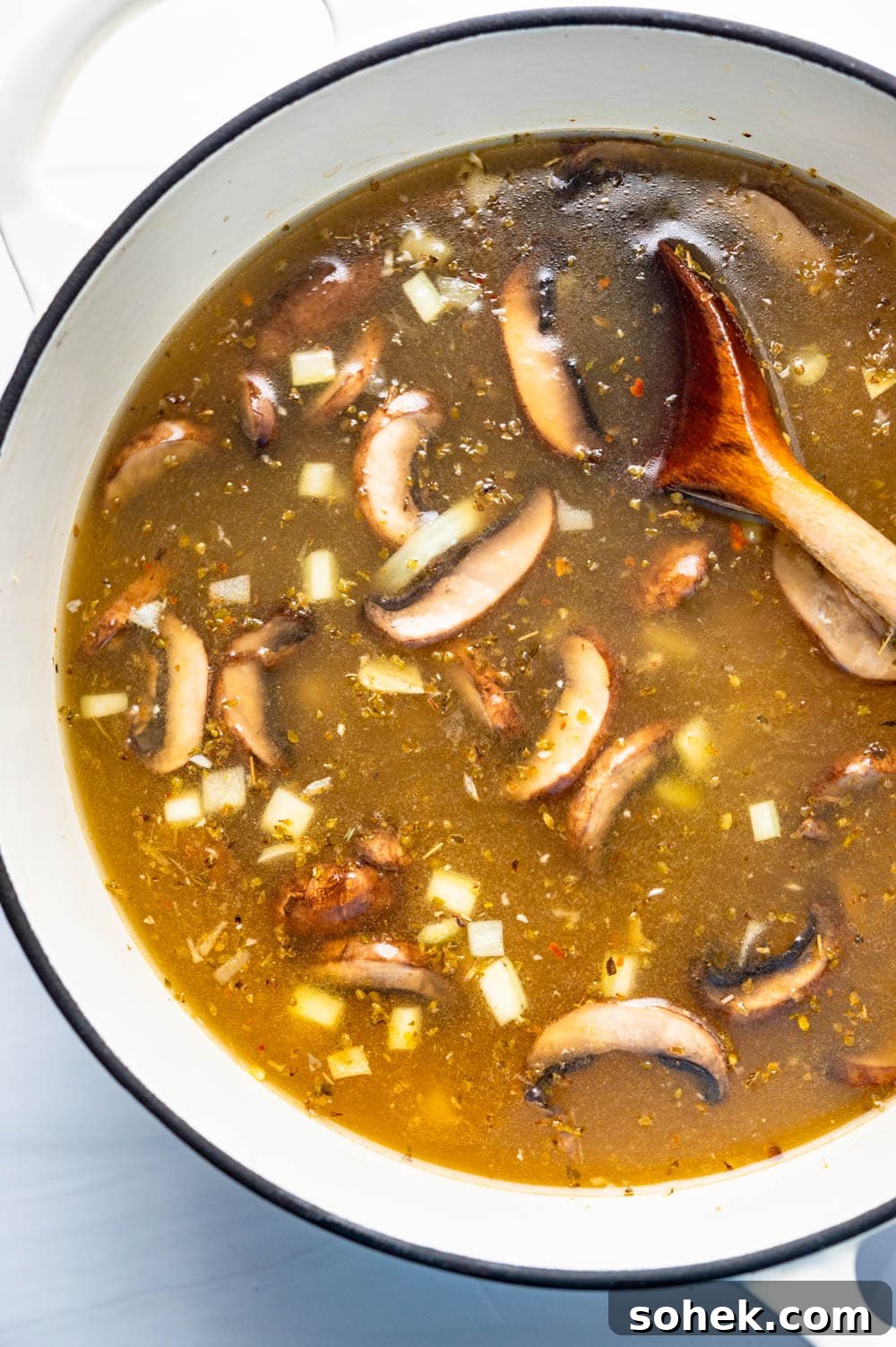 adding chicken broth to Greek chicken soup.