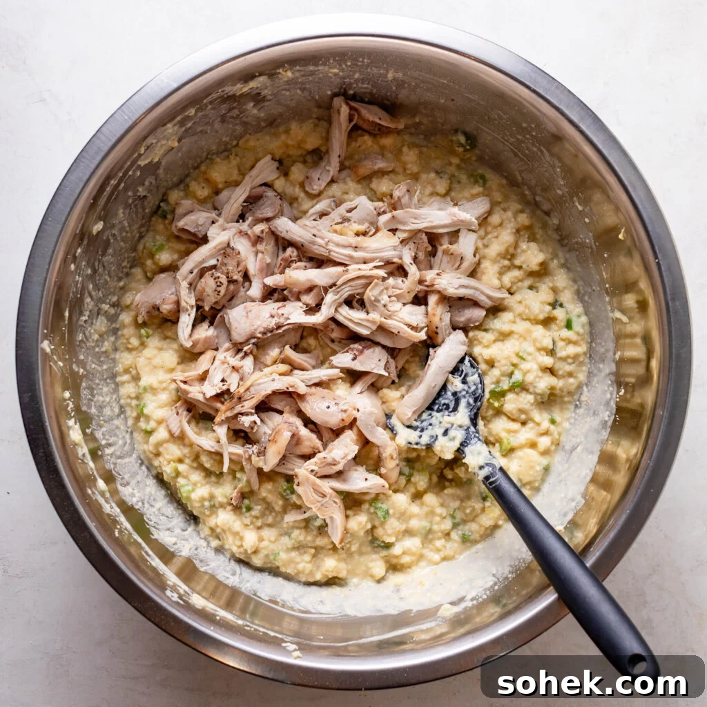 Adding cooked pulled chicken to the cornbread dressing mix. 