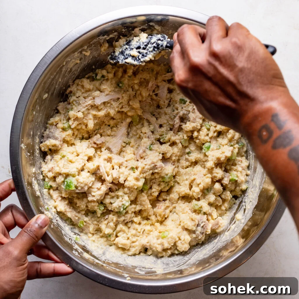 Stirring the chicken and cornbread dressing mix in a silver mixing bowl. 