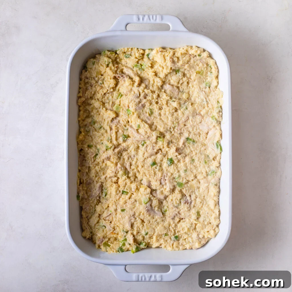 chicken and cornbread dressing mix in a white casserole dish with the top smoothed out. 