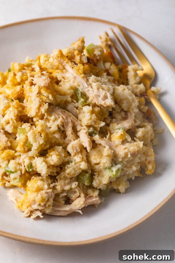 Chicken and cornbread dressing on a white and gold plate with a gold fork