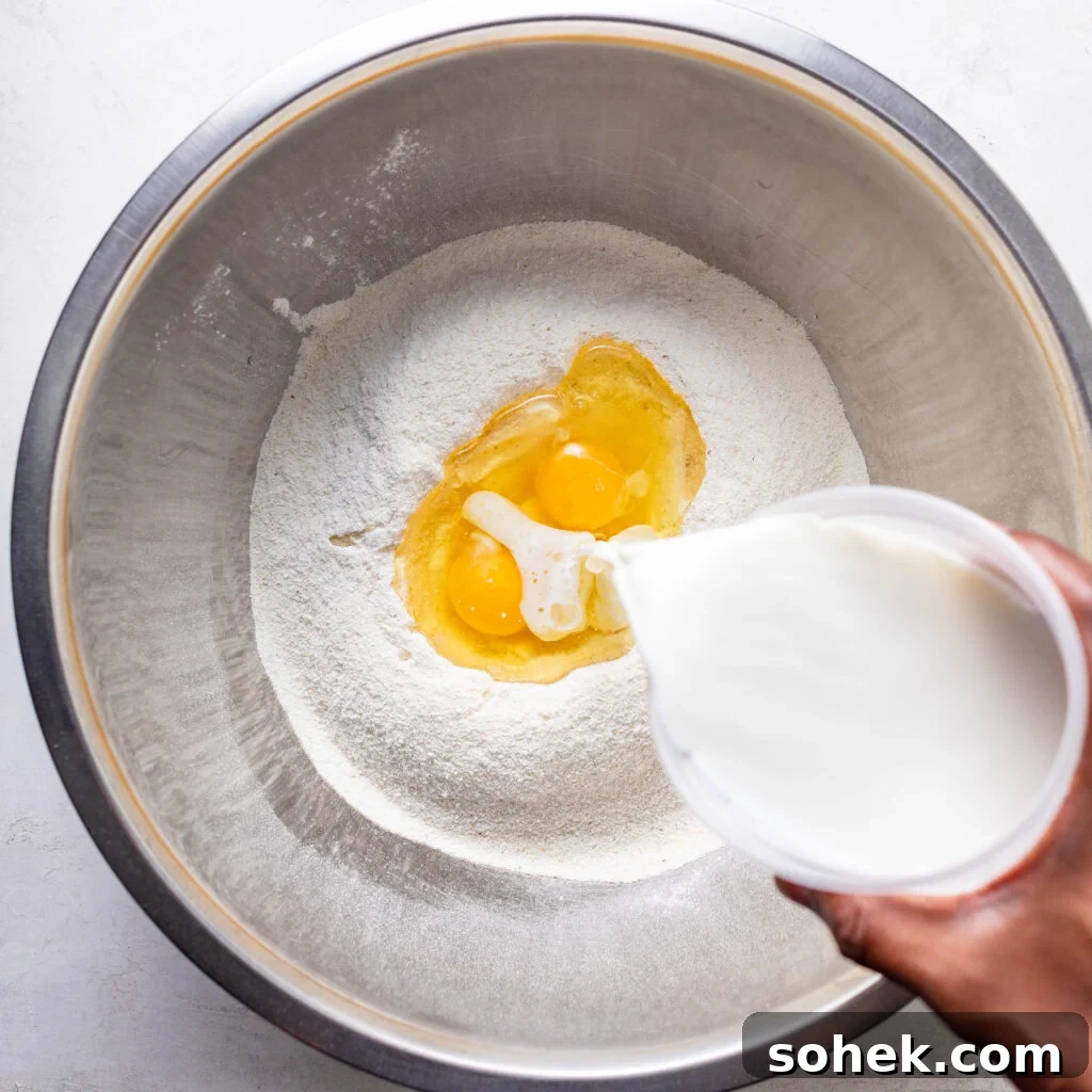 Pouring buttermilk in a mixing bowl with cornmeal oil, and eggs