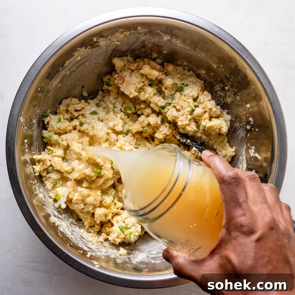 Pouring chicken broth into the chicken and cornbread dressing mix. 