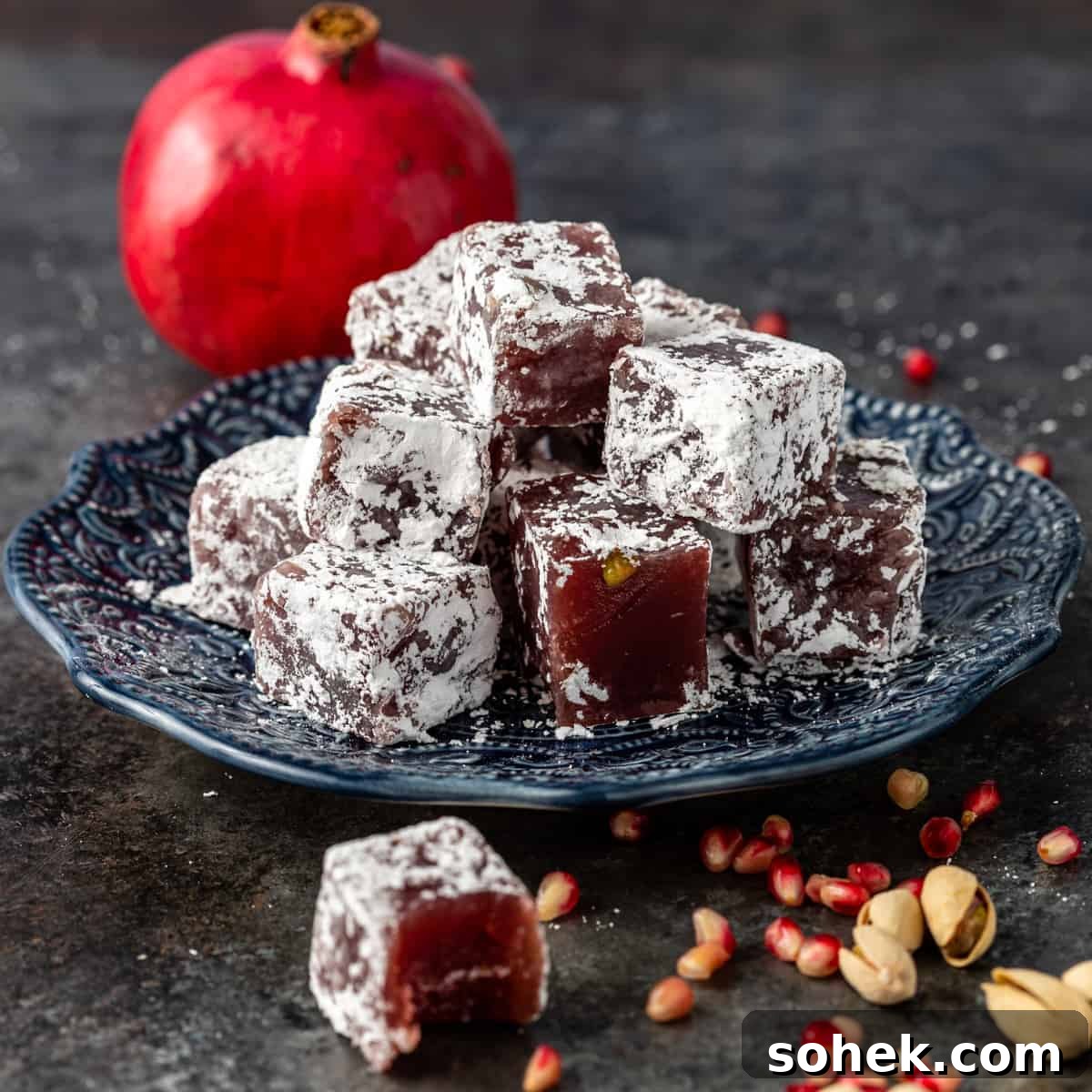 Authentic Turkish Delight (Lokum) Recipe for Soft, Chewy Sweets 2 lokum on blue plate with pomegranate in background