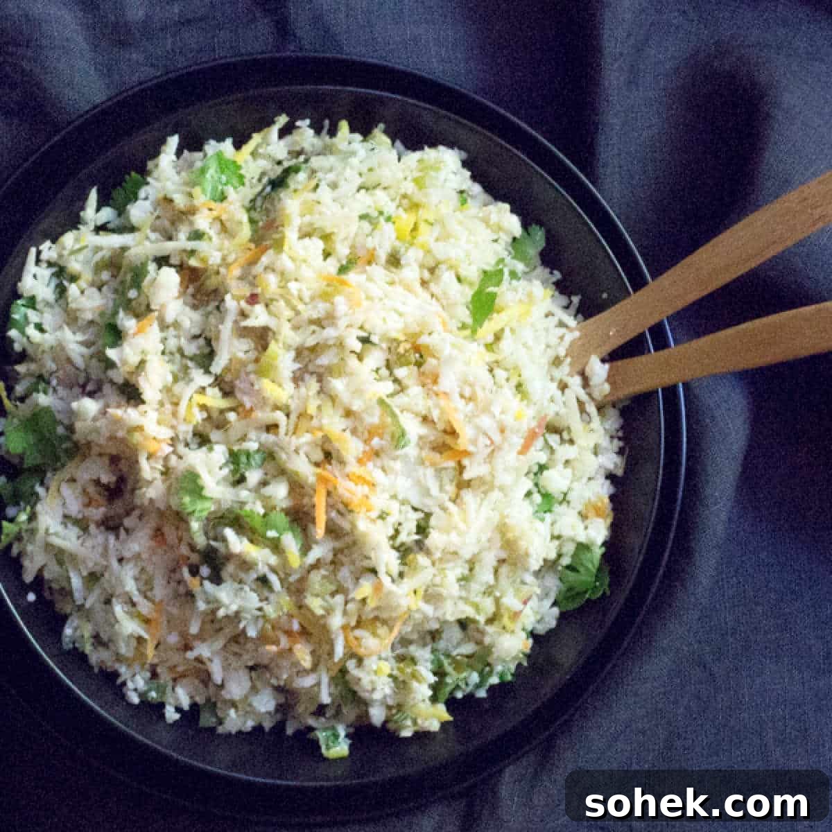 Cilantro Lime Cauliflower Rice with Coconut Milk 2 A bowl of cauliflower rice sauteed with carrots with 2 serving spoons.