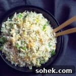 Cilantro Lime Cauliflower Rice with Coconut Milk 3 A bowl of cauliflower rice sauteed with carrots with 2 serving spoons.