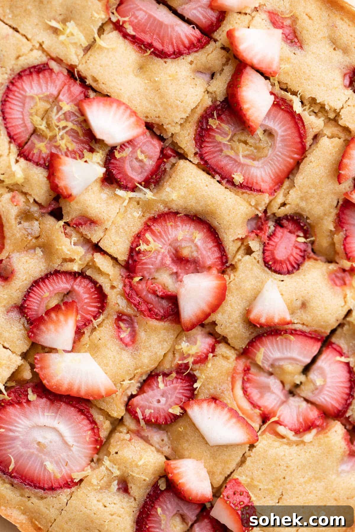Strawberry lemon bars topped with fresh strawberries and fresh lemon zest.