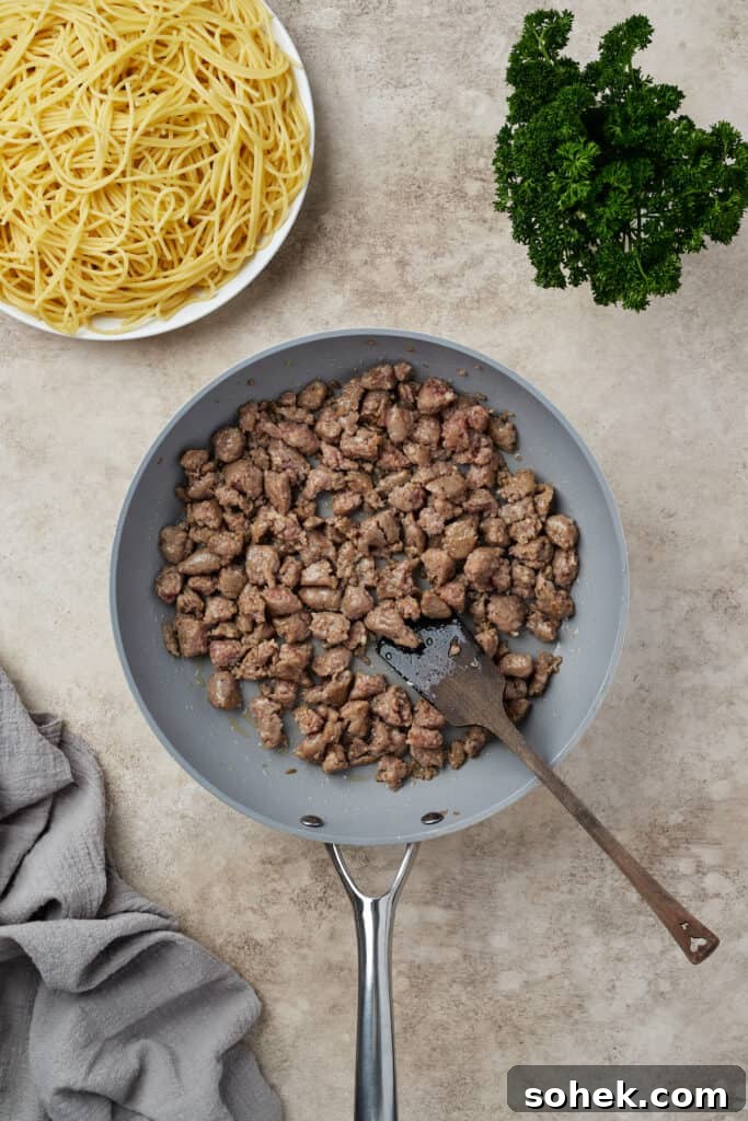 Italian sausage frying in a skillet.