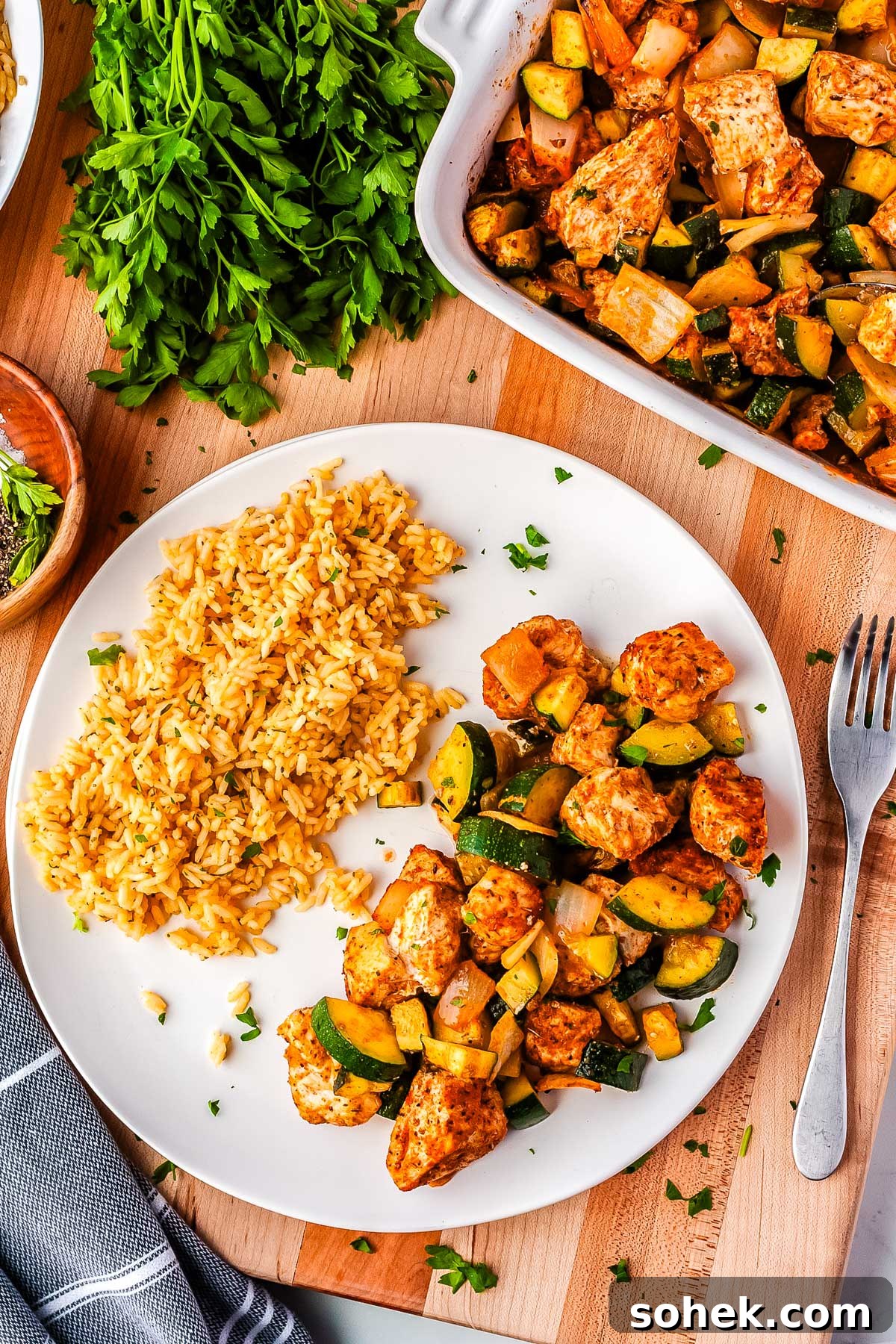 An overhead picture of chicken, zucchini, and rice on a white dinner plate. 