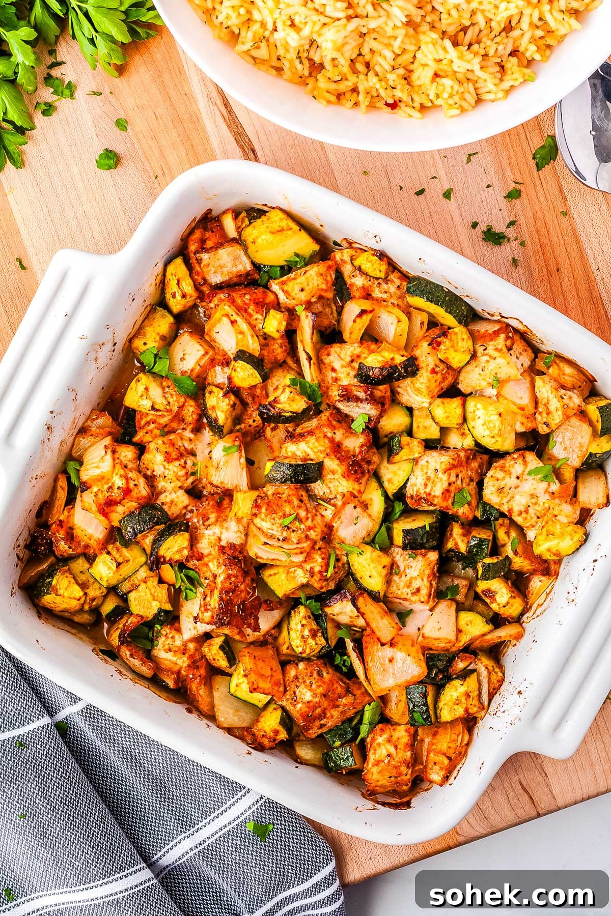 An overhead picture of the finished chicken zucchini baked on a wooden cutting board with rice in the background.