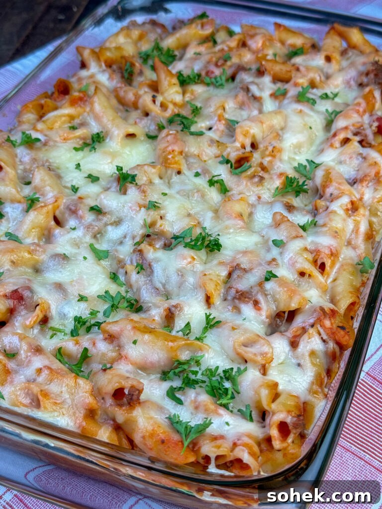 Cheese melted over a warm pasta casserole with ground beef, sauce and parsley garnishing the top.