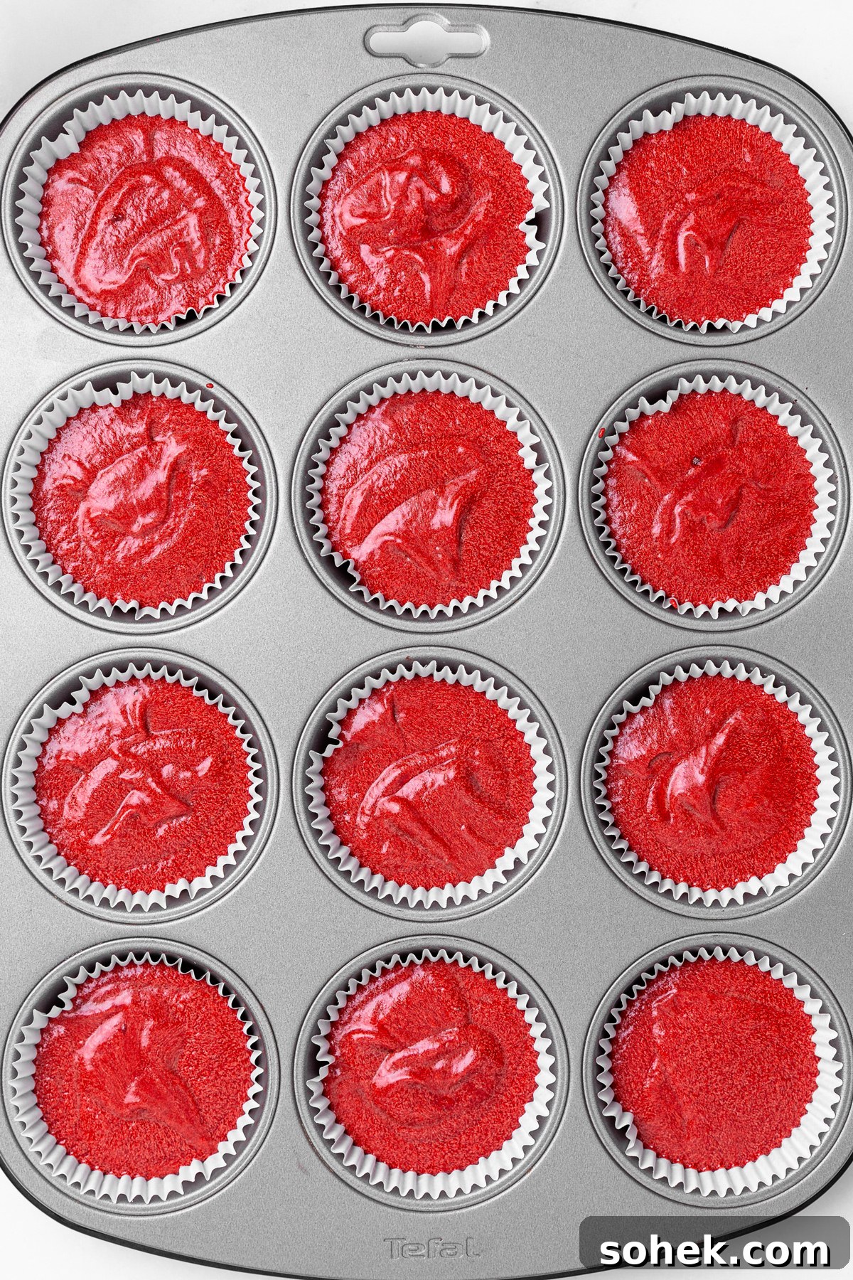 unbaked red velvet cupcake batter in lined muffin pan