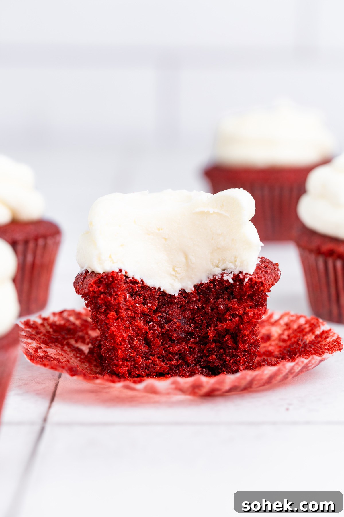 cut red velvet cupcake showing the soft crumb and frosting