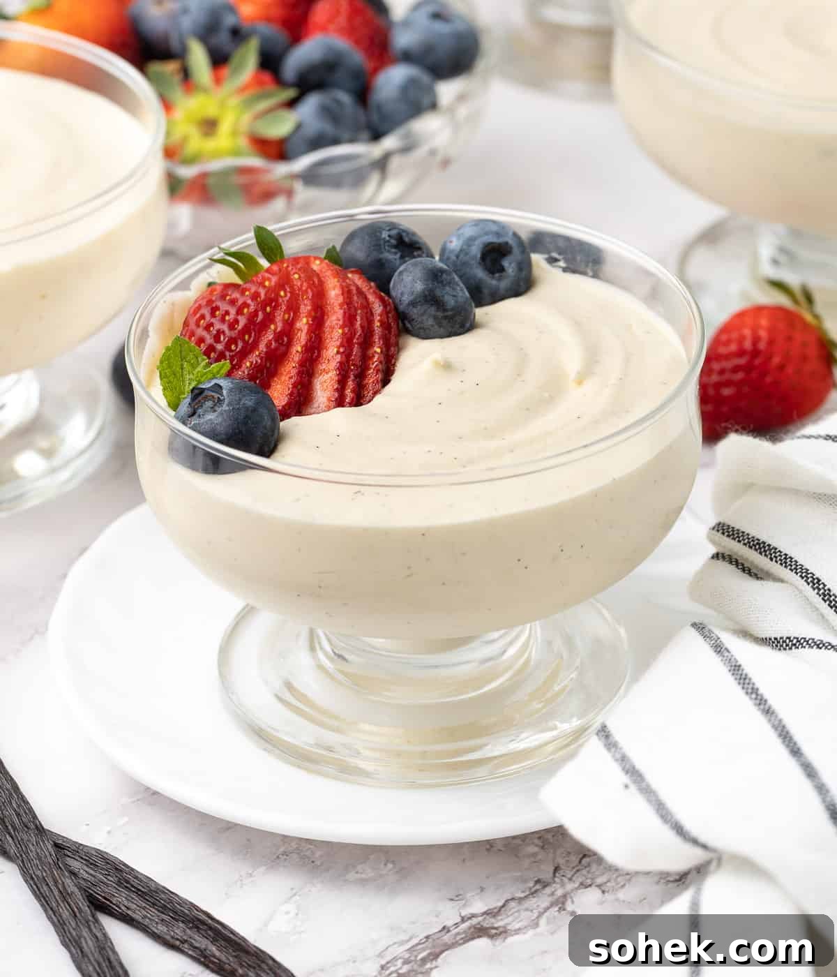 Mousse topped with fresh berries placed over a small white plate.