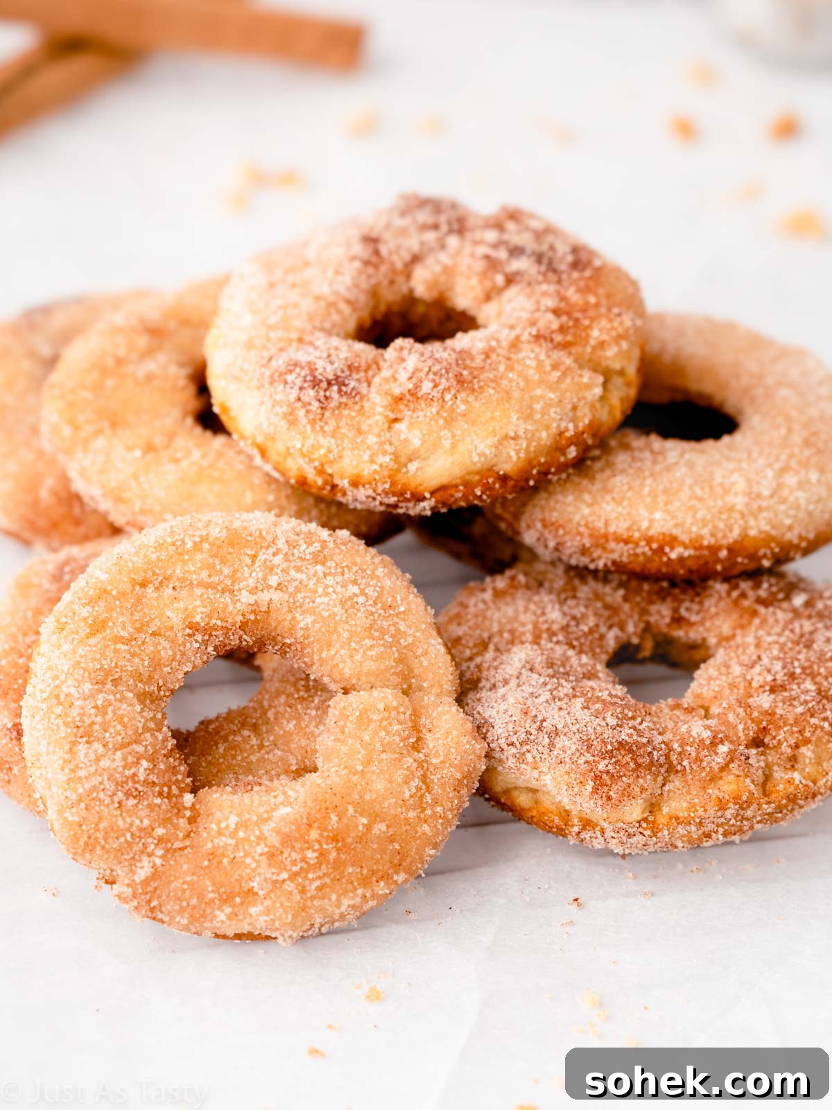 Stack of gluten free apple cider donuts topped with cinnamon sugar.
