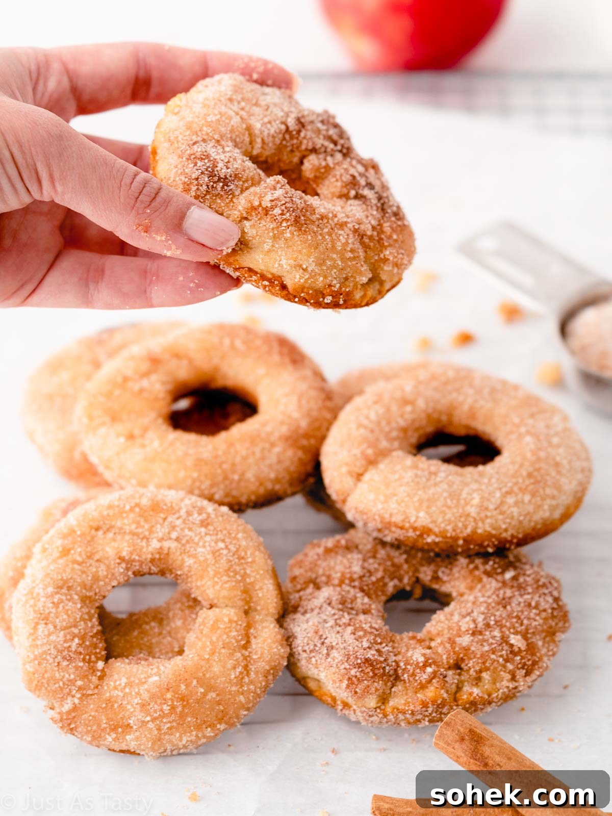 A hand picking up an apple cider donut.