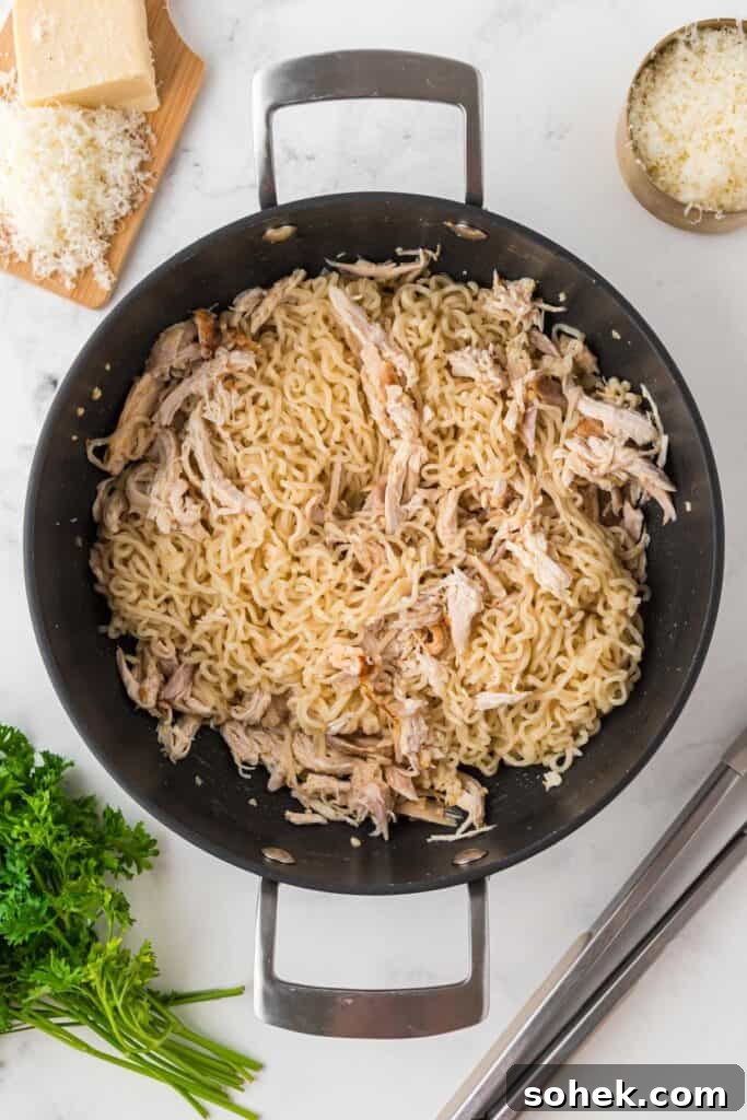 Adding cooked ramen noodles to skillet with chicken and garlic