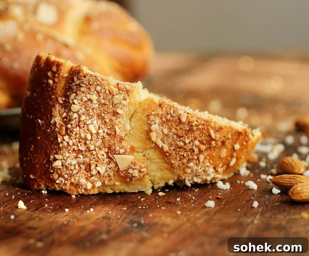 On a wooden table a single piece of crunchy topped holiday bread, pearl sugar and almonds around