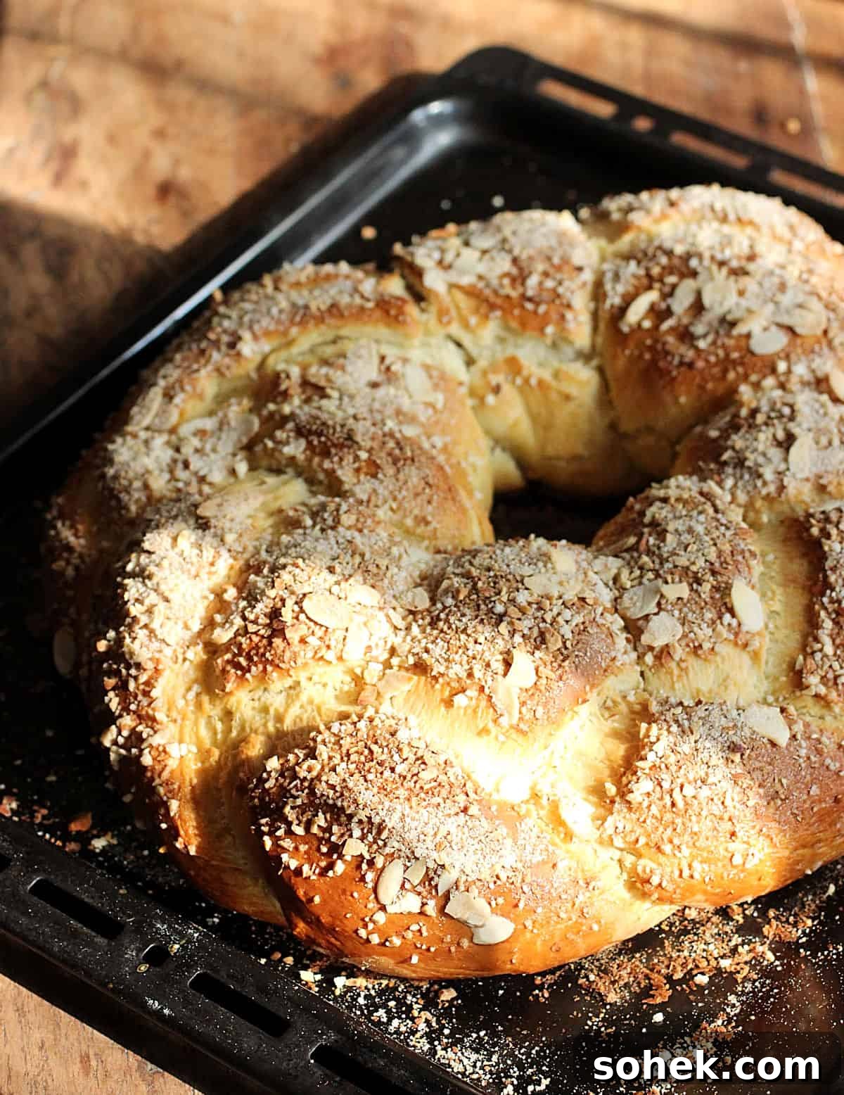 Just baked almond braided bread on black oven pan.