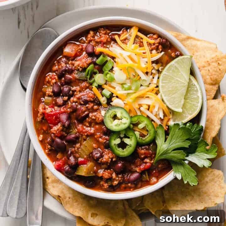 A bowl of chili garnished with cheese and jalapenos.