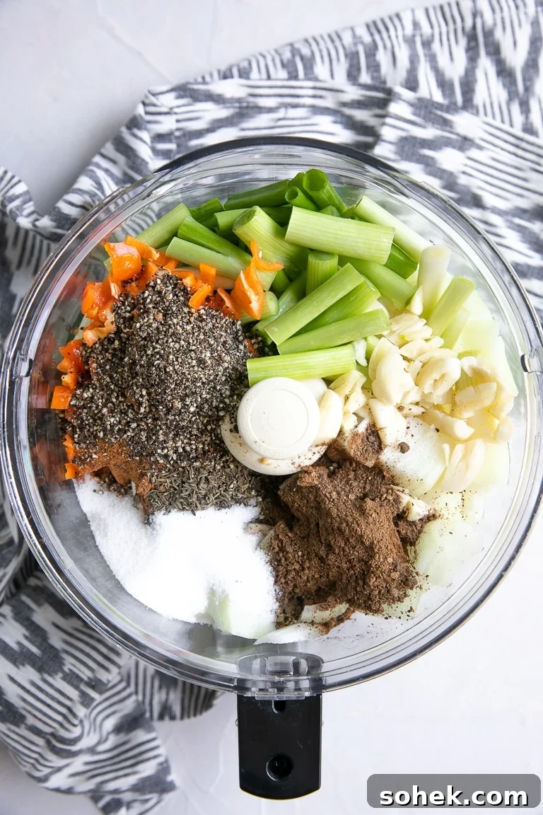 Food processor filled with green onions, garlic, onions, allspice, salt, pepper, and habanero.