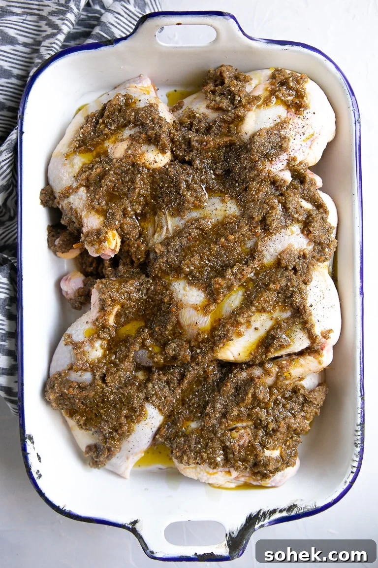 Raw chicken in a baking dish covered in jerk marinade.