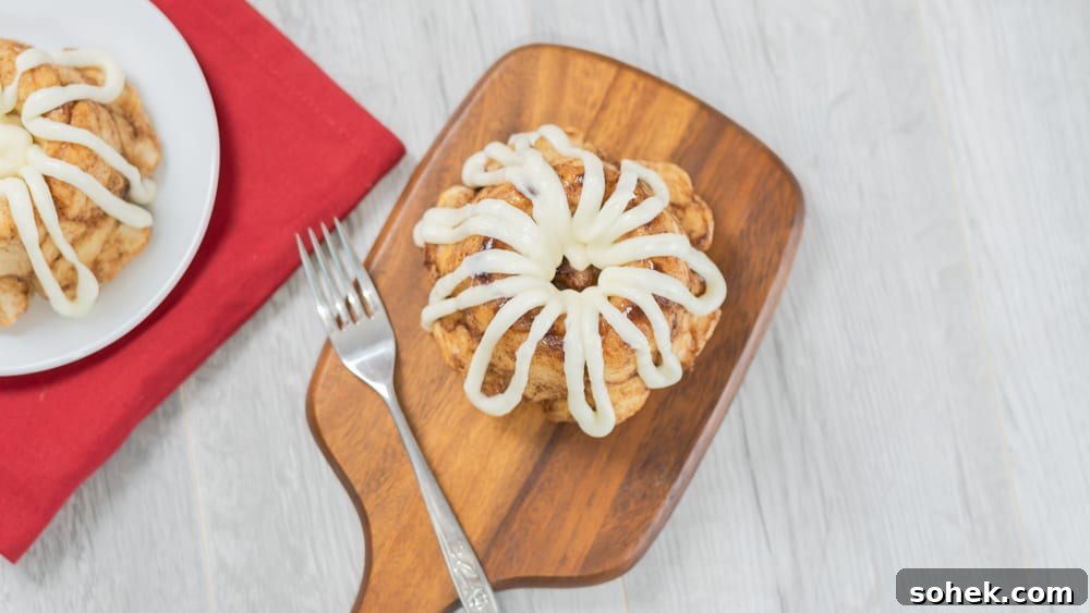 Mini bundt cinnamon sugar pull-apart bread with cream cheese glaze serving board fork with rose red napkin.
