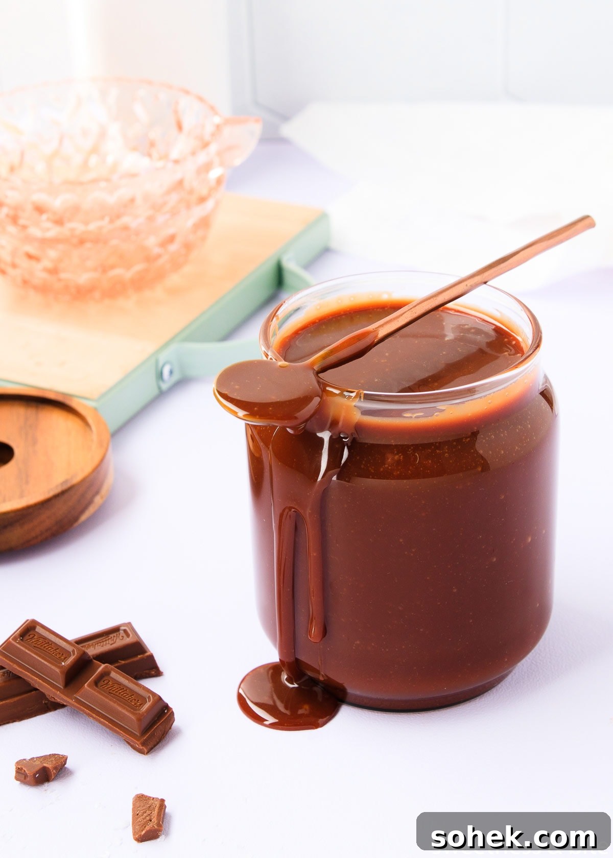 The sauce in a glass jar, with a long-handled copped spoon resting on top, and a big drip of sauce dripping from the end of the spoon, down the side of the jar.