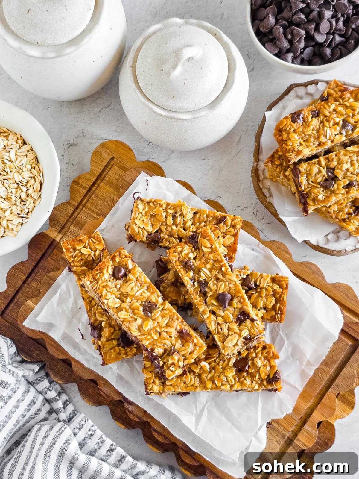 Chewy Einkorn Granola Bars with chocolate chips on parchment paper, on a wooden cutting board.